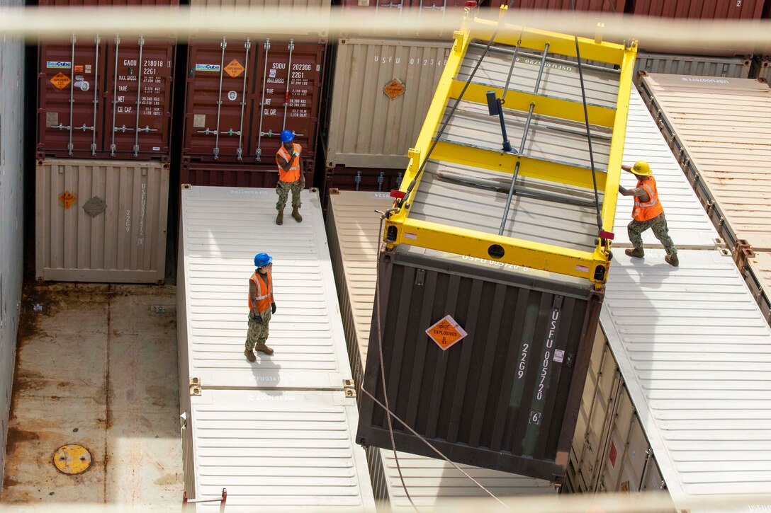 Sailors move cargo aboard a ship.