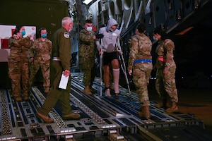 A group of 316th Operational Medical Readiness Squadron aerospace medical technicians and corpsmen from Walter Reed National Military Medical Center assist a wounded service member departing a C-17 Globemaster 3 to board a medical transport bus at Joint Base Andrews, Md., July 7, 2022