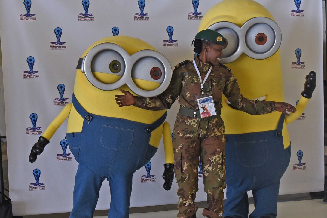 Soldier stands between two people dressed in costumes.