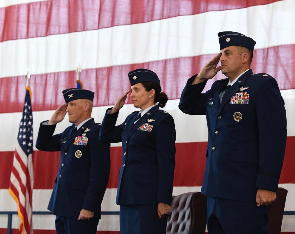 Col. Derek Oakley, the 28th Operations Group commander, left, Lt. Col. Kristina Ellis, the outgoing 28th Operations Support Squadron commander, middle, and Lt. Col. Jerad Rich, the incoming 28th Operations Support Squadron commander, right, render a salute during the national anthem at Ellsworth Air Force Base, S.D., July 08, 2022.