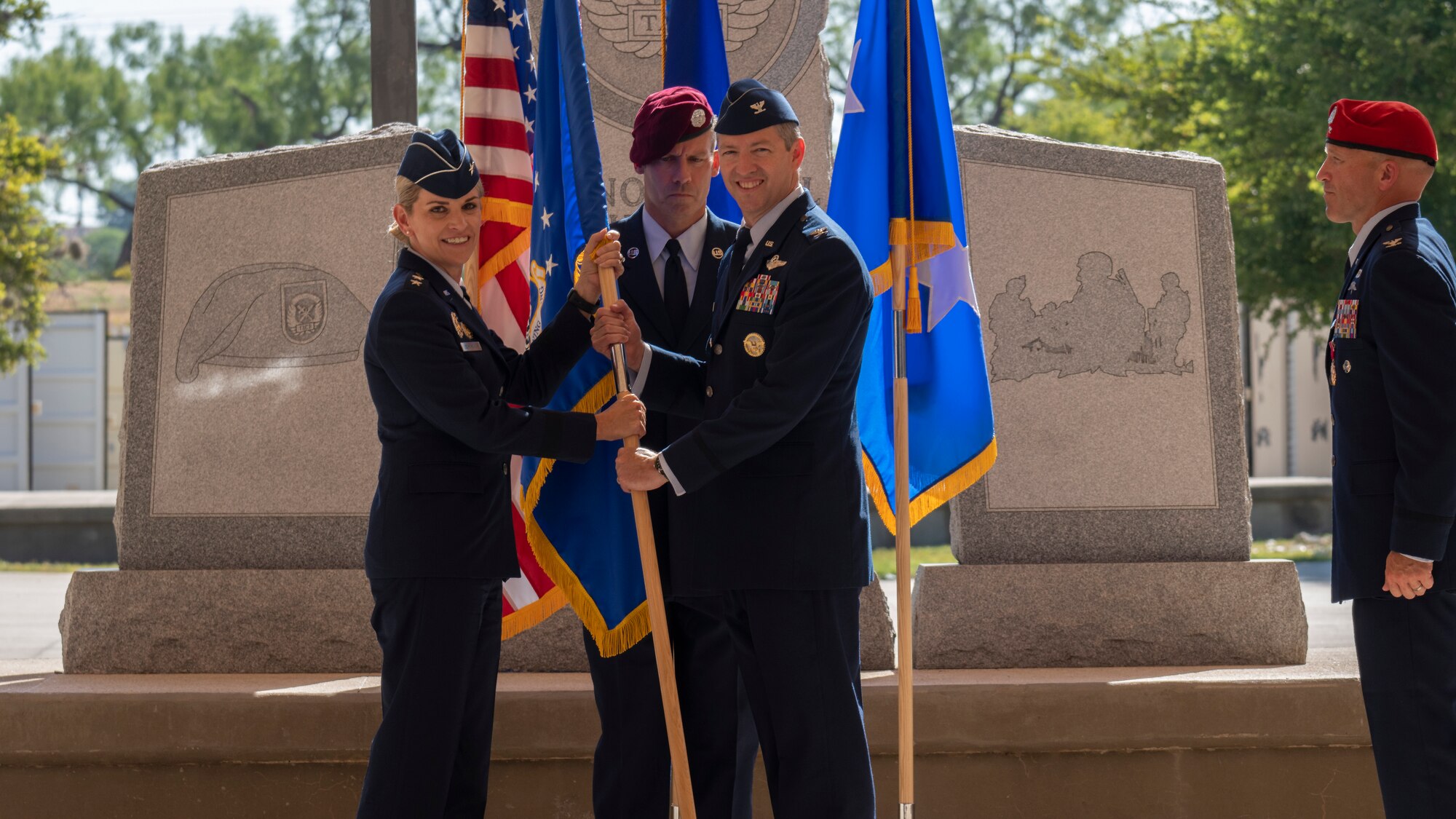 U.S. Air Force Maj. Gen. Michele Edmondson (left), 2nd Air Force commander and presiding officer, passes the guidon to Col. Nathan Colunga (middle), incoming Special Warfare Training Wing commander, during the SWTW change of command ceremony at Joint Base San Antonio-Chapman Training Annex, Texas, July 11, 2022. At right is Col. Mason Dula, outgoing SWTW commander.