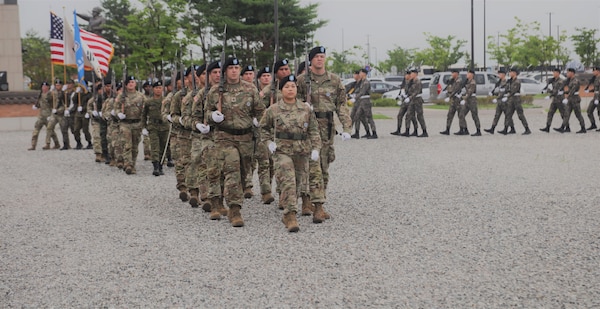 Members with the United Nations Command conduct a pass and review during a ceremony.