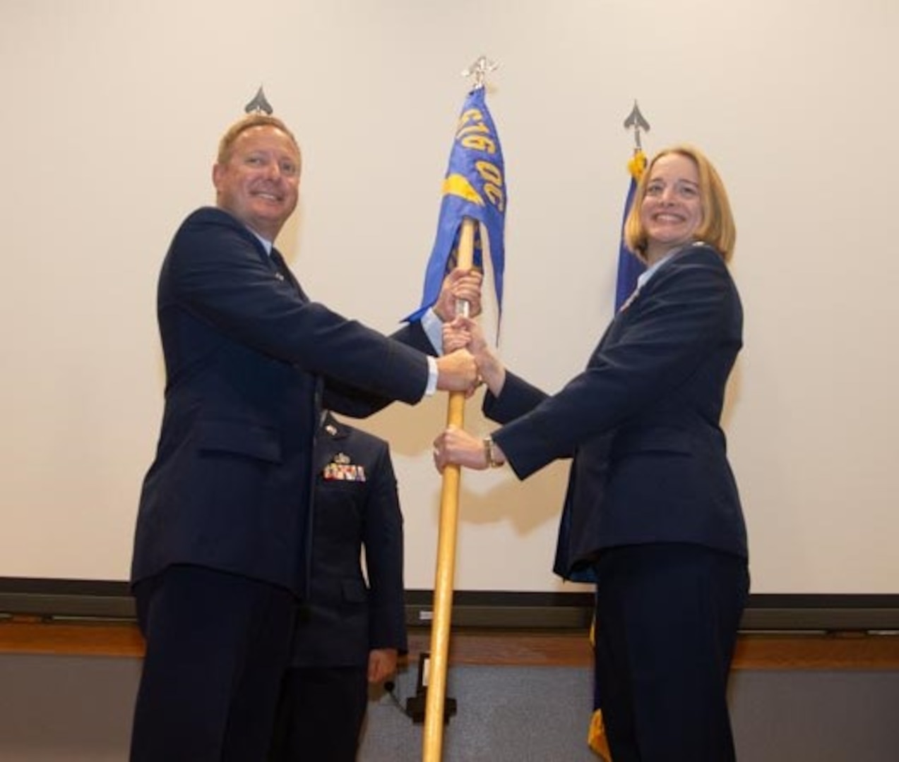 Officer in uniform passes flag to new commander.