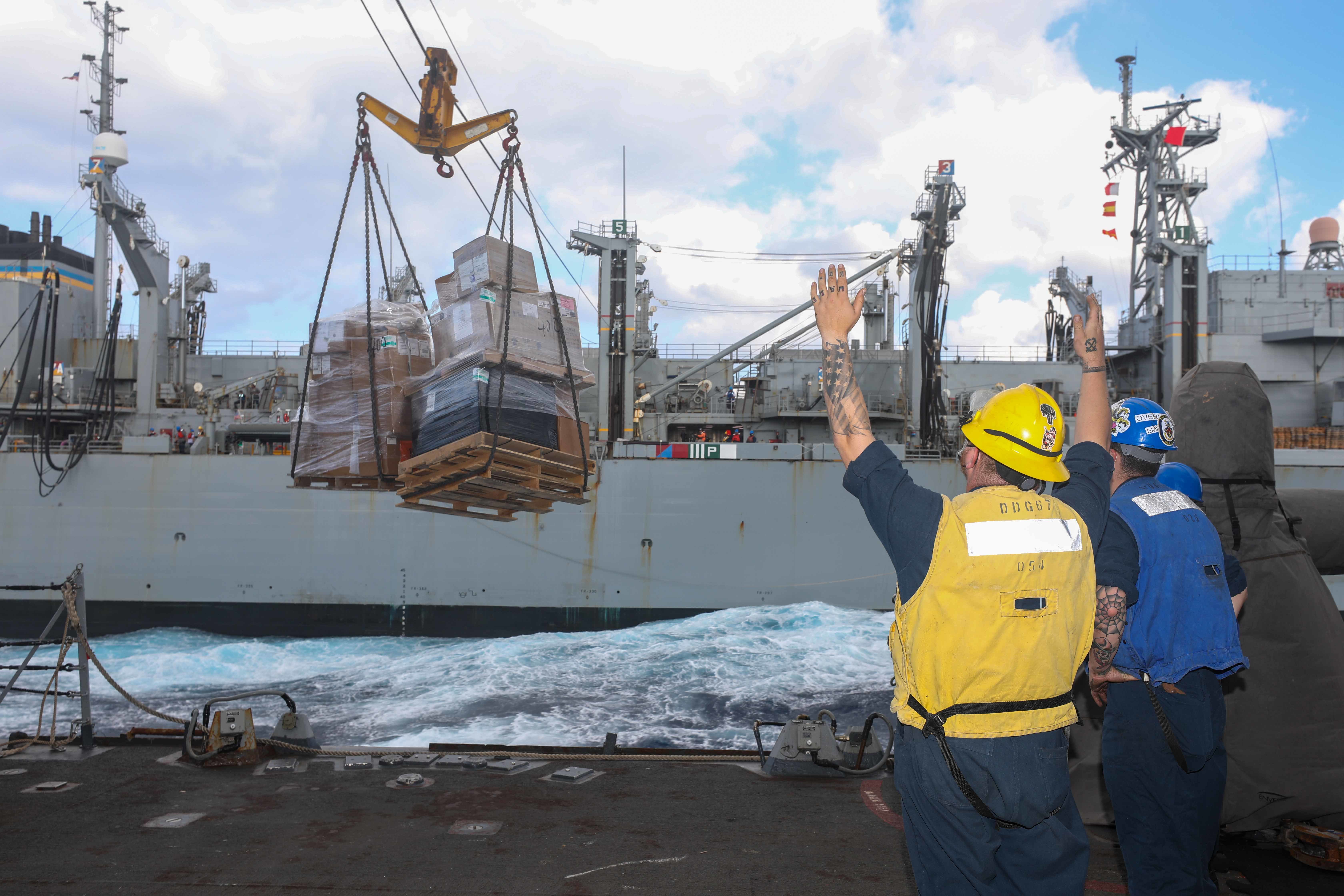A Sailoe guides pallets during a replenishment-at-sea with the Military Sealift Command fast combat support ship USNS Supply (T-AOE 6) aboard USS Cole (DDG 67) in the Ionian Sea, July 9, 2022.
