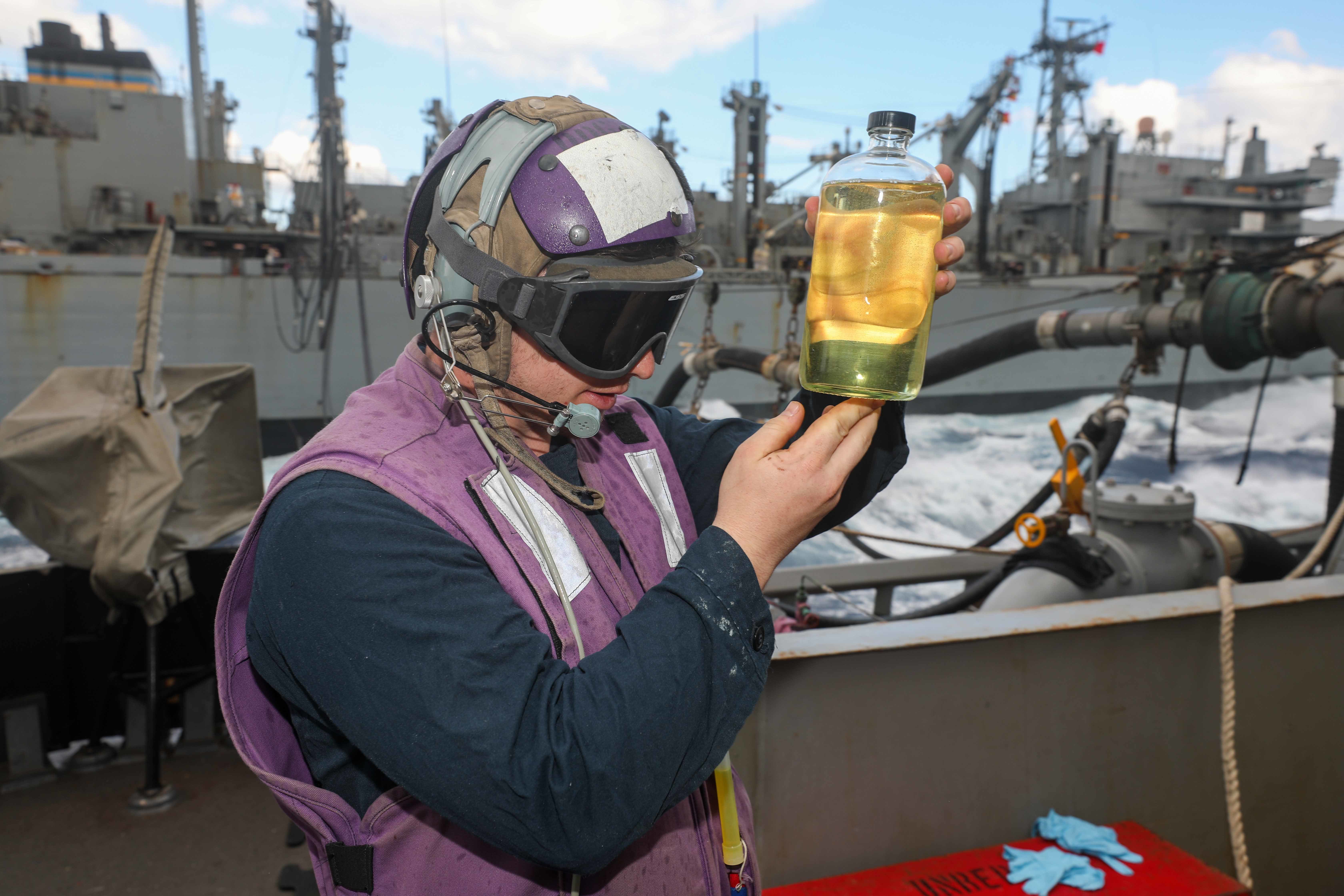 A Sailor examines a fuel sample during a replenishment-at-sea with the Military Sealift Command fast combat support ship USNS Supply (T-AOE 6) aboard USS Cole (DDG 67) in the Ionian Sea.