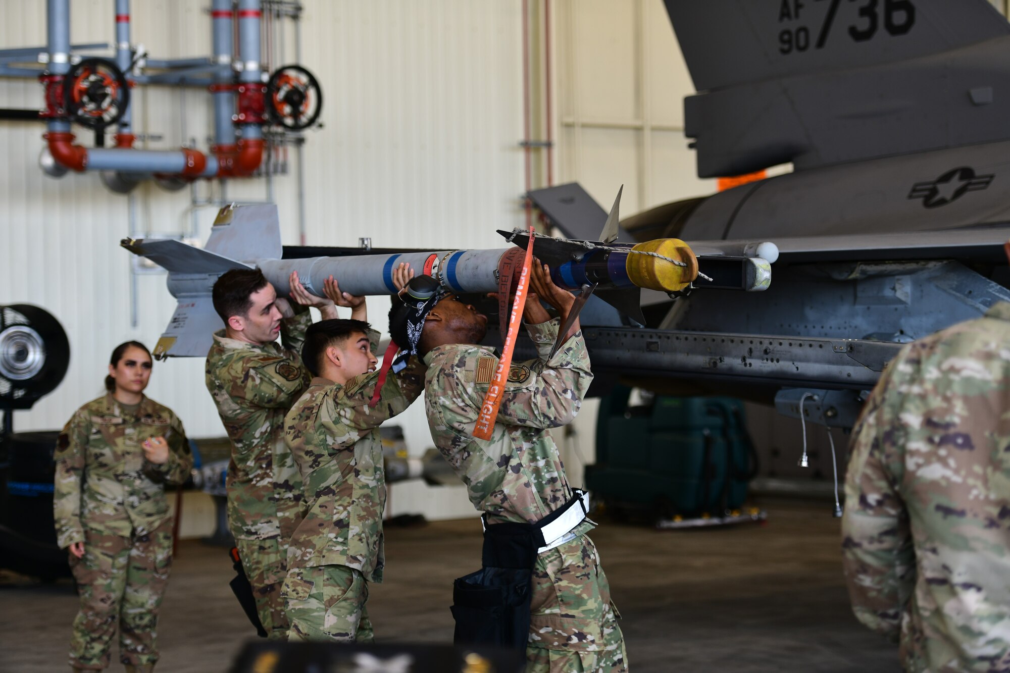 Airmen lifting a missile.