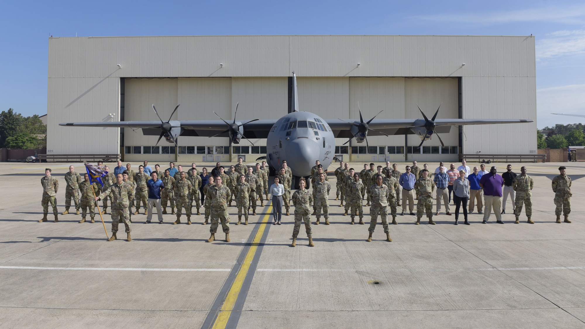 A large group of people standing in formation in front of an aircraft.