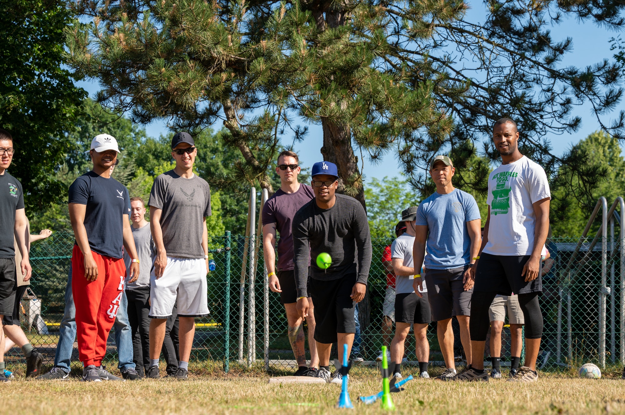 A group of people standing around one person tossing a lawn dart.