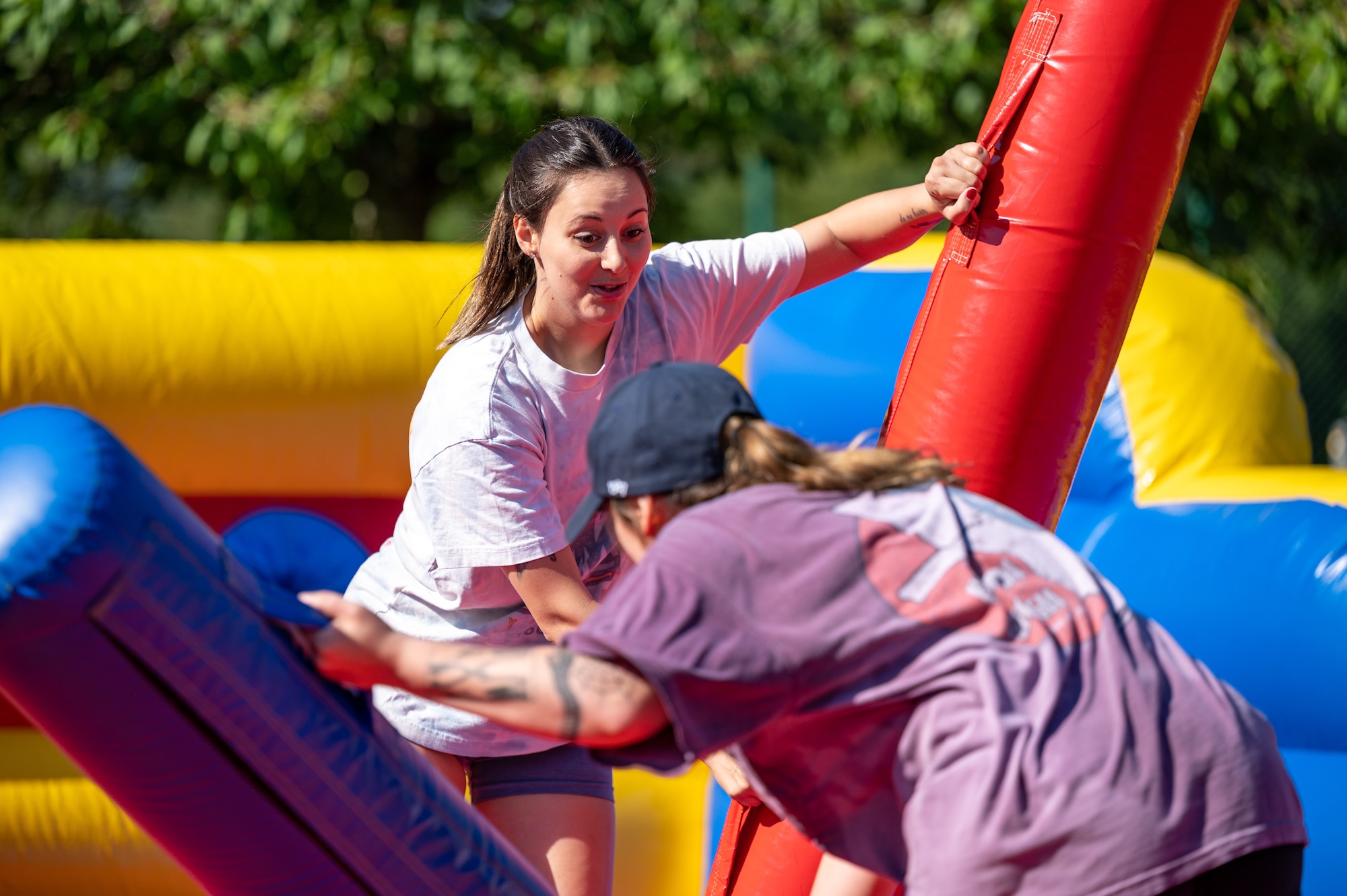 Two people holding inflatable jousting sticks.