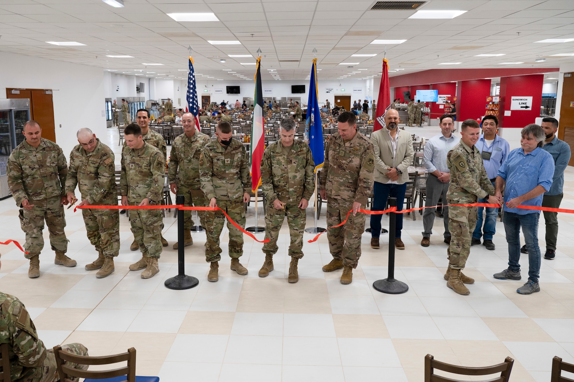 Leadership from the 386th Air Expeditionary Wing, 386th Expeditionary Force Support Squadron, 386th Expeditionary Civil Engineer Squadron, and U.S. Army Corps of Engineers celebrate the opening of the Desert Winds dining facility at Ali Al Salem Air Base, Kuwait, July 6, 2022. The dining facility's handiwork highlights the teamwork and enduring presence of the 386th Air Expeditionary Wing and its mission partners. (U.S. Air Force photo by Staff Sgt. Dalton Williams)