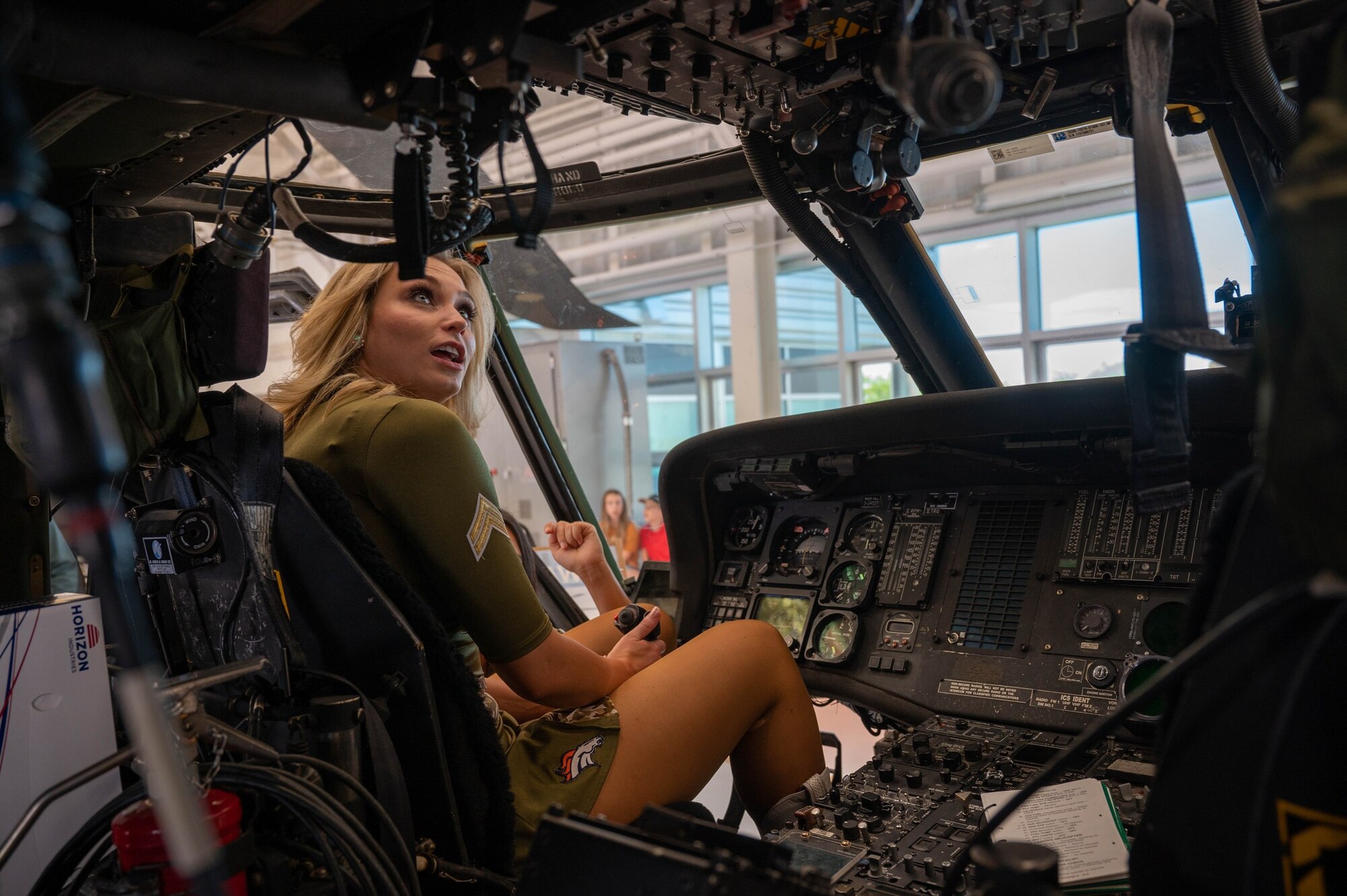 A Denver Broncos cheerleader sits inside a UH-60 Black Hawk helicopter at Army Aviation on Buckley Space Force Base, Colo., July 8, 2022. Members from the Denver Broncos learned about various aircraft while visiting Army Aviation. (U.S. Space Force photo by Senior Airman Haley N. Blevins)