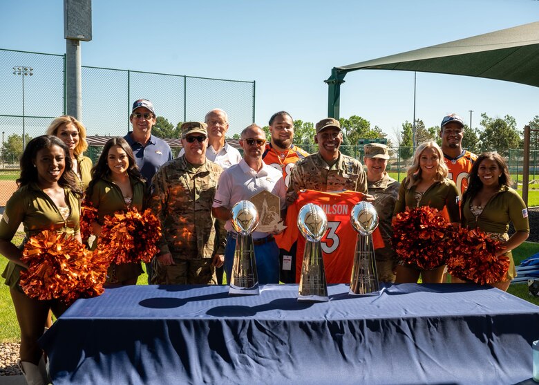 Space Base Delta 2 leadership poses for a group photo with Denver Broncos players, alumni, and cheerleaders at Buckley Space Force Base, Colo., July 8, 2022. The Denver Broncos visited Buckley to tour multiple facilities and host a meet and greet for members of Buckley. (U.S. Space Force photo by Senior Airman Haley N. Blevins)