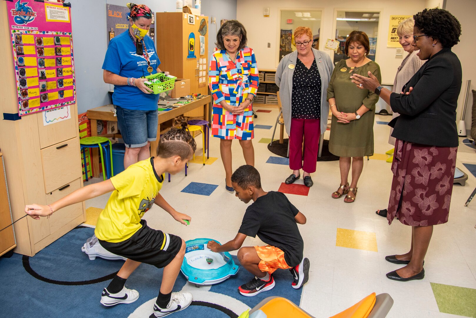 Ladies watch children play in a childcare classroom.