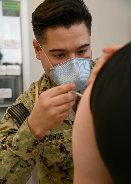 A sailor gives a patient a shot.