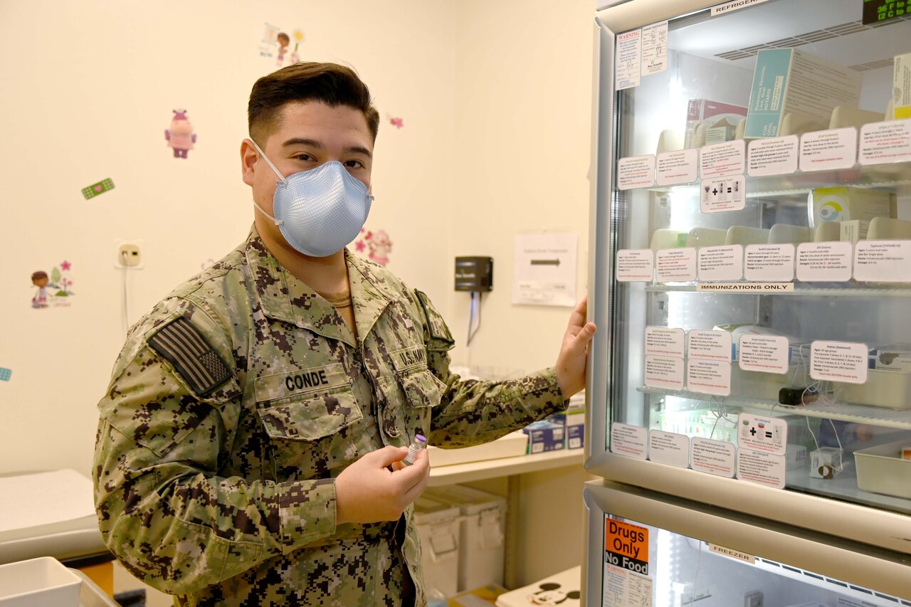 A sailor poses by a medical refrigeration unit.