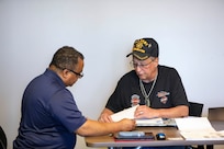 Forrest Powell, left, deputy director, state of Alaska Office of Veterans Affairs, assists local veterans with their earned benefits during an outreach event at the Aurora Inn in Nome, Alaska, July 9, 2022. During the two-day event in Nome 22 veterans filed claims for benefits that they earned through military service. (Alaska National Guard photo by 1st Lt. Balinda O’Neal)