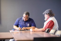 Forrest Powell, left, deputy director, state of Alaska Office of Veterans Affairs, assists local veterans with their earned benefits during an outreach event at the Aurora Inn in Nome, Alaska, July 9, 2022. During the two-day event in Nome 22 veterans filed claims for benefits that they earned through military service. (Alaska National Guard photo by 1st Lt. Balinda O’Neal)