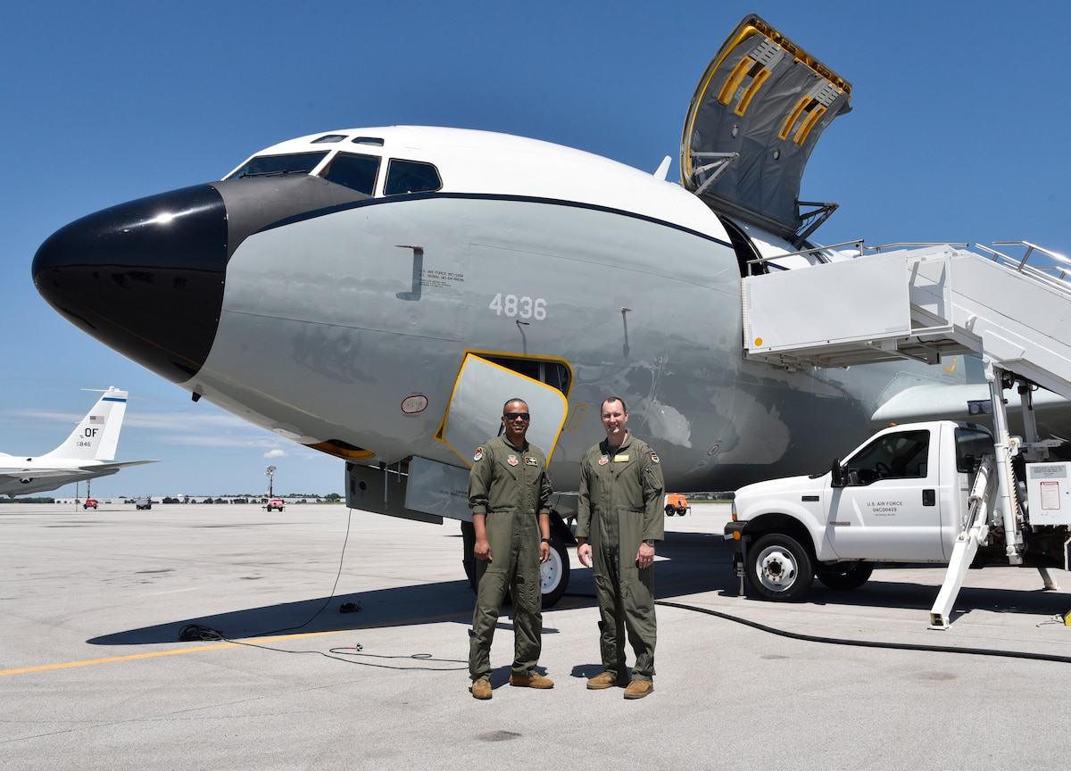 Two men in flight suits standing in front of a WC-135R plane