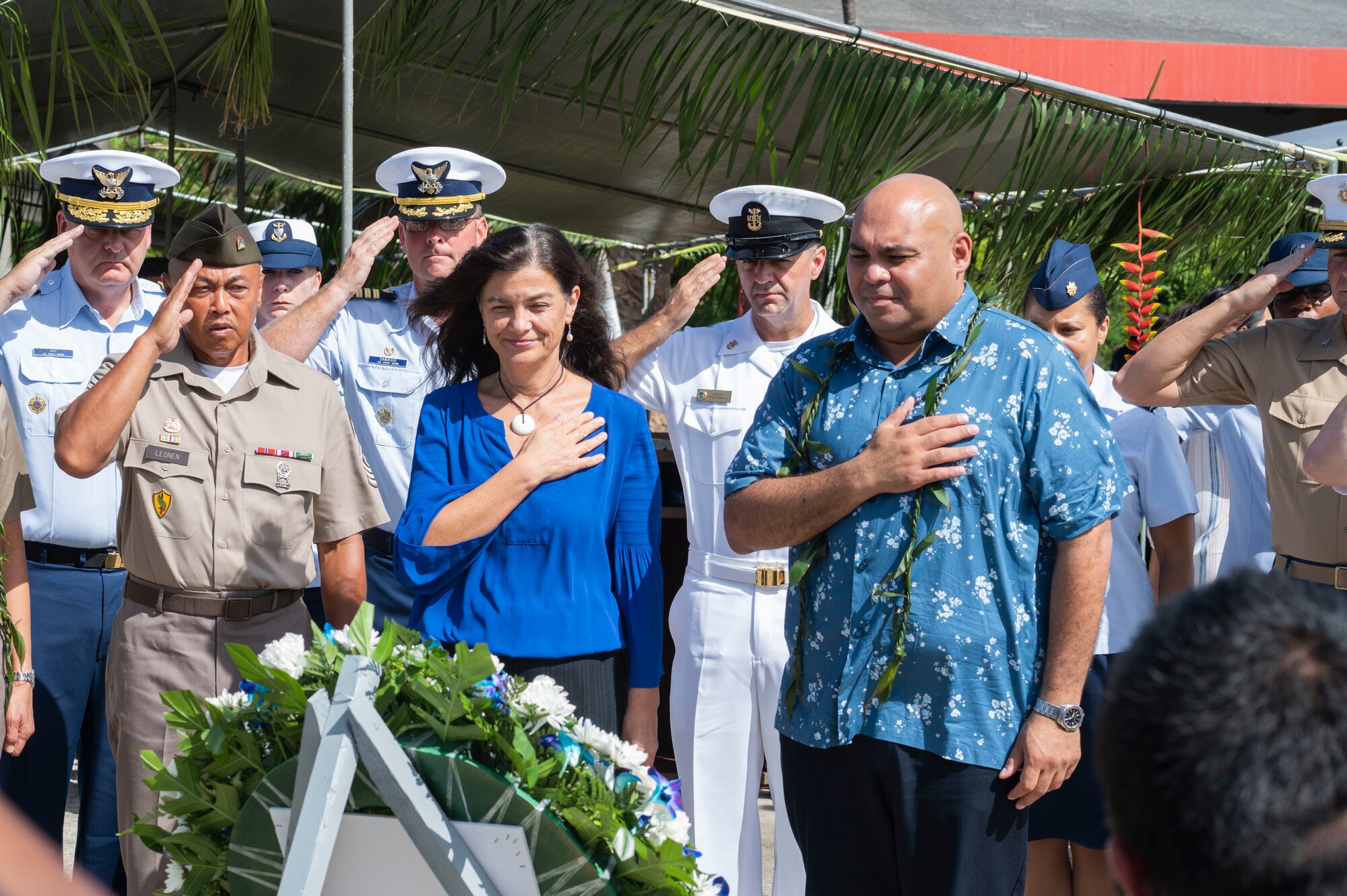 People saluting in front of a wreath.