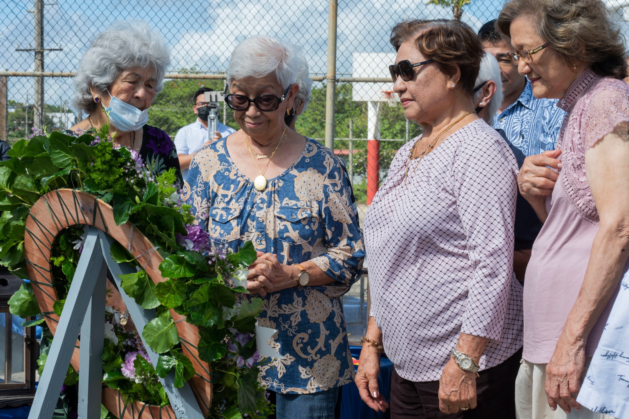 Women standing next to a wreath.