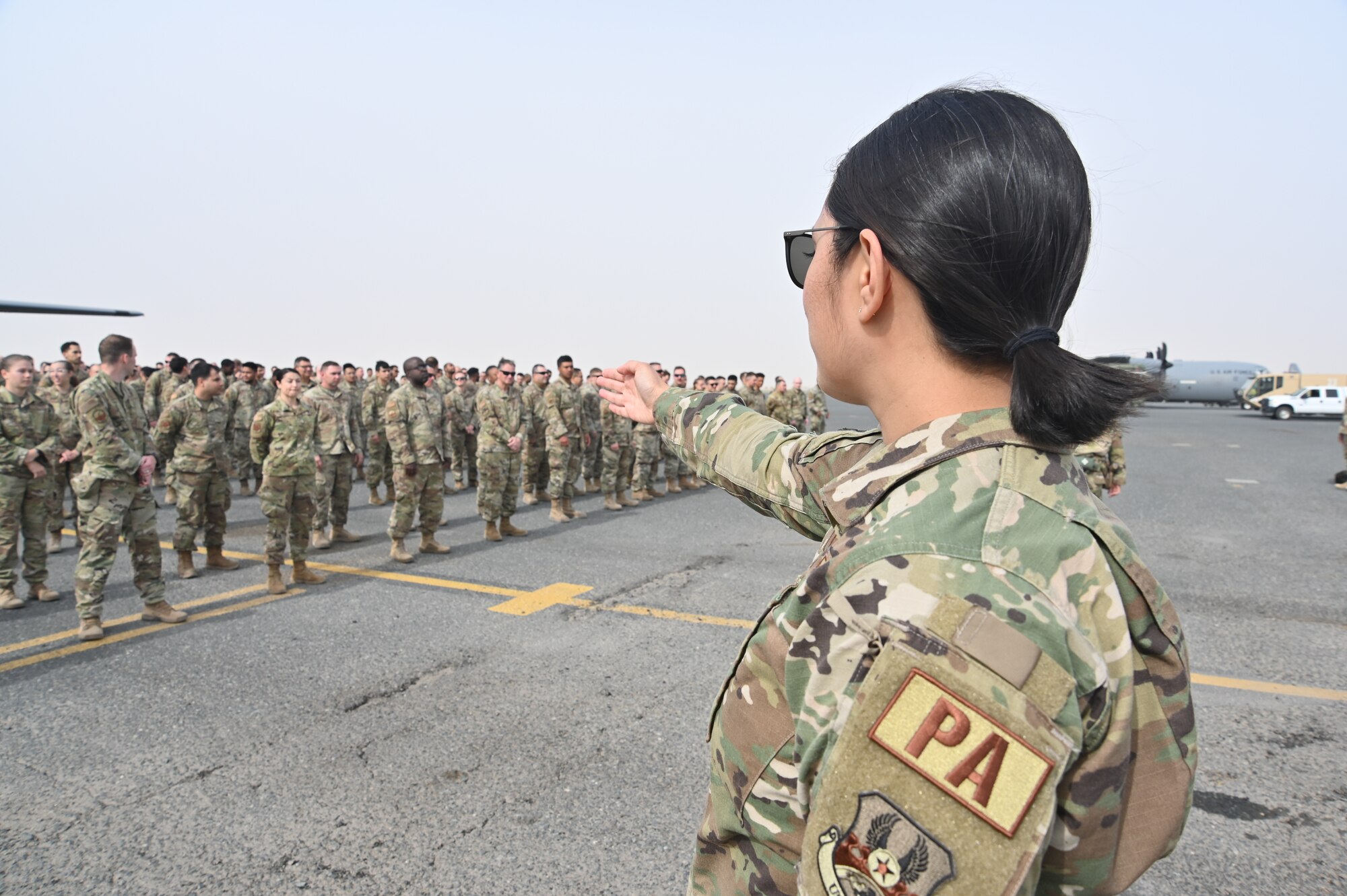 U.S. Air Force Capt. Melissa Heintz, 386th Air Expeditionary Wing chief of public affairs, directs service members to fall in formation during an official group photo of the 386th Air Expeditionary Wing at Ali Al Salem Air Base Kuwait, March 3, 2022. The official group photo served as a historical documentation of the members who deployed to the 386th AEW. (U.S. Air Force photo by Master Sgt. Arthur Wright)