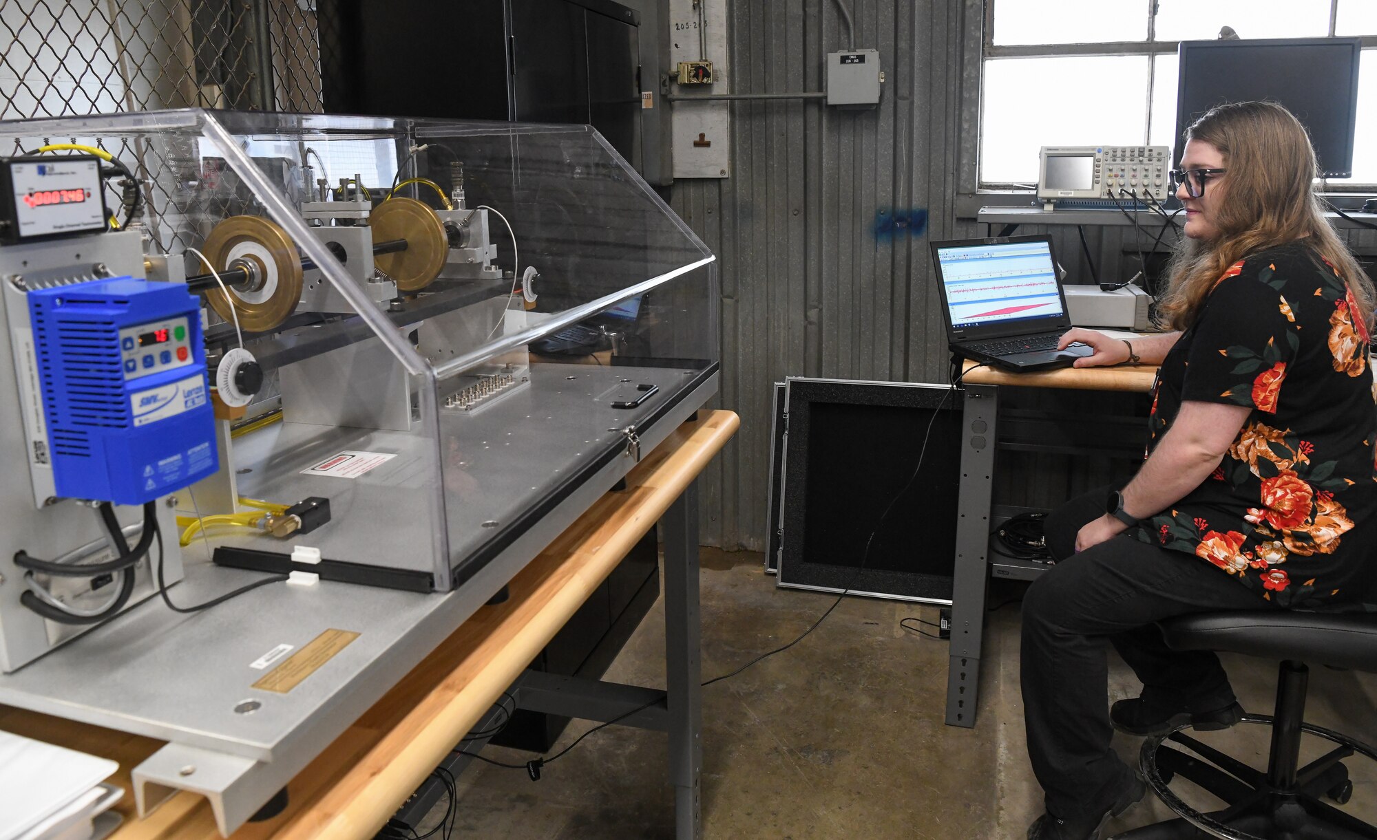 Parke Nation, an Arnold Engineering Development Complex mechanical reliability engineer, watches a Condition-Based Maintenance Fault Simulator as she monitors vibration data displayed on a computer, June 8, 2022, at the Innovation Center at Arnold Air Force Base, Tennessee. The simulator was pitched in an AEDC Spark Tank proposal and identified as a beneficial addition to the Innovation Center for condition-based maintenance training. (U.S. Air Force photo by Jill Pickett)