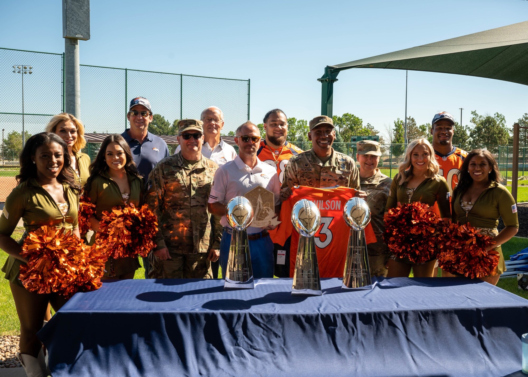 Space Base Delta 2 leadership poses for a group photo with Denver Broncos players, alumni, and cheerleaders at Buckley Space Force Base, Colo., July 8, 2022. The Denver Broncos visited Buckley to tour multiple facilities and host a meet and greet for members of Buckley. (U.S. Space Force photo by Senior Airman Haley N. Blevins)