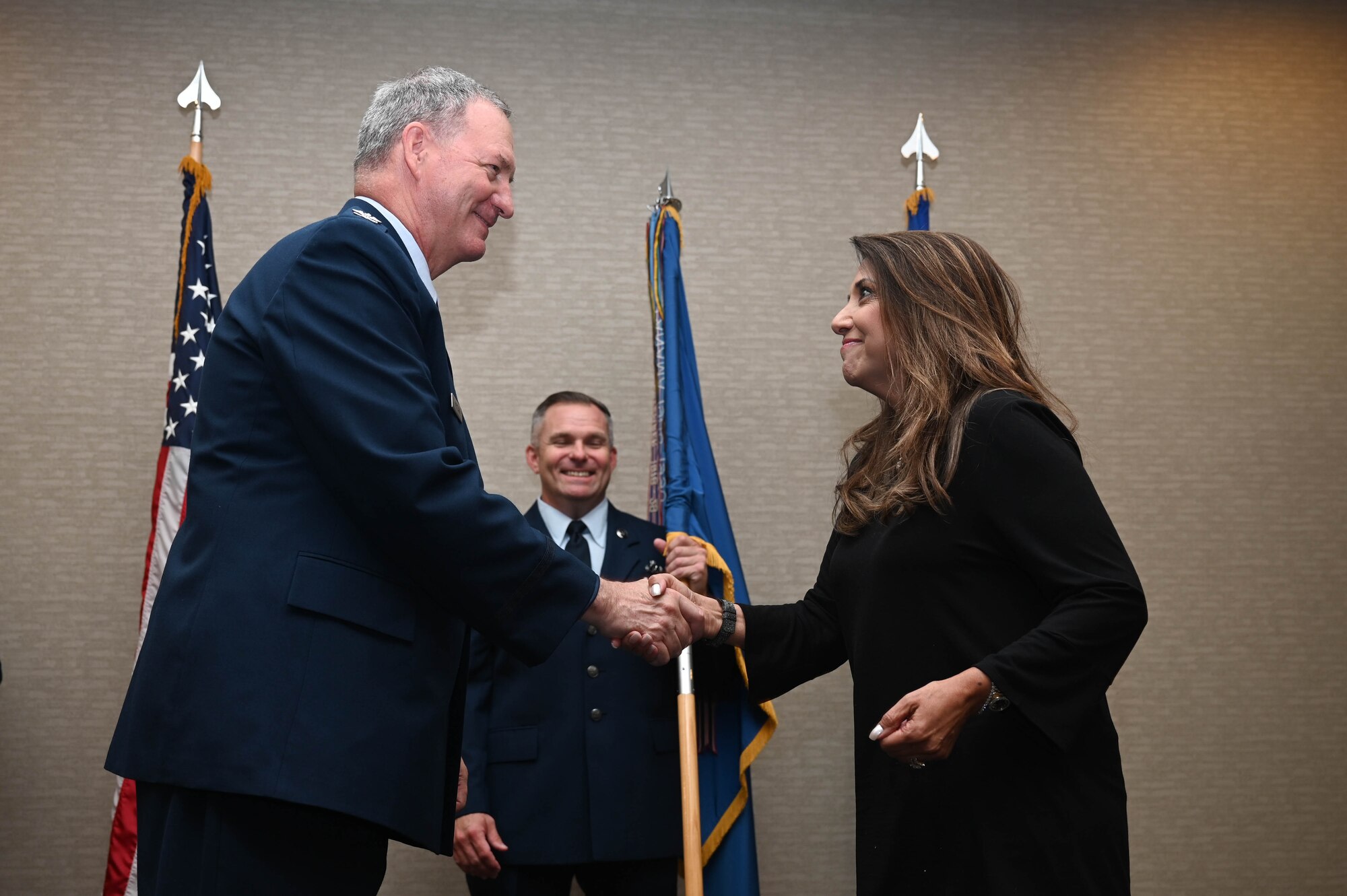Col. Terry McClain, 433rd Airlift Wing commander, and Bianca Rhodes, Knight Aerospace president and CEO, shake hands during the 433rd AW Honorary Commanders’ Induction Ceremony in San Antonio, July 9, 2022. The ceremony included each honorary commander receiving an Air Force commander’s insignia pin and assuming honorary command by accepting the 433rd AW guidon. (U.S. Air Force photo by Senior Airman Brittany Wich)