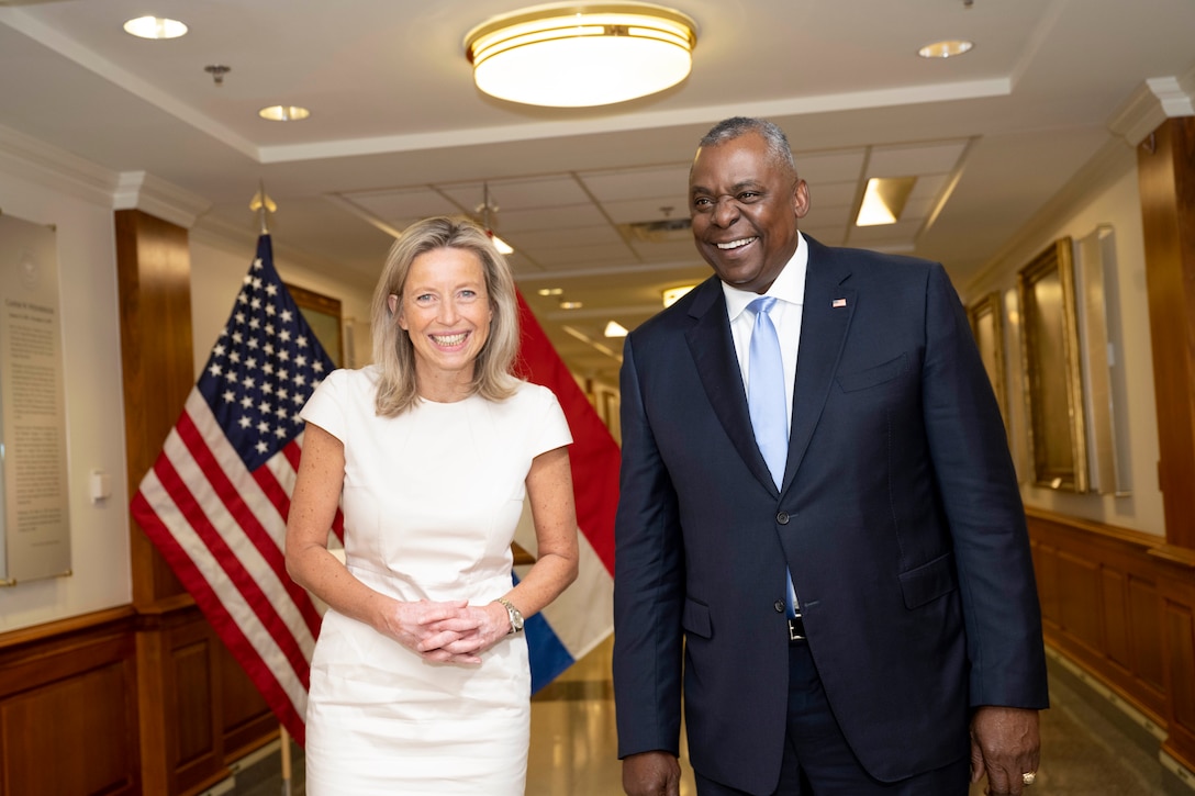 Two defense officials pose before Dutch and U.S. flags.