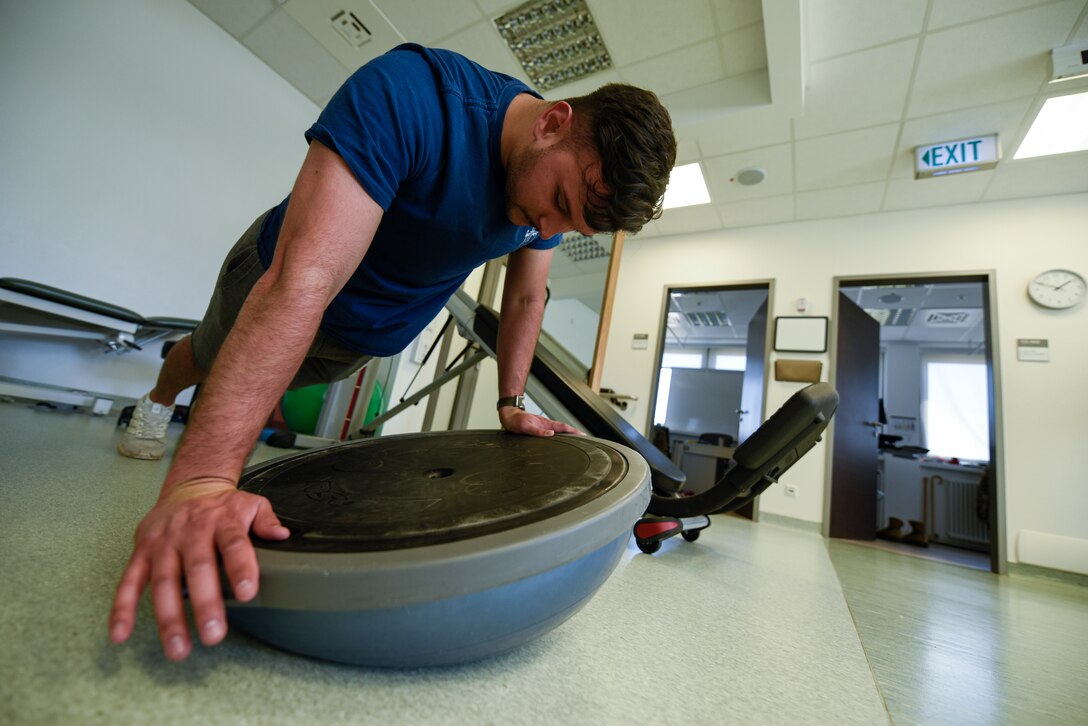 U.S. Air Force Senior Airman John Cabral, 52nd Security Forces member, performs a physical therapy exercise in the medical clinic at Spangdahlem Air Base, Germany, June 14, 2022. Providing an avenue for Airmen to rehabilitate on base helps 52nd Fighter Wing Airmen to maintain physical readiness to support worldwide Air Force operations. (U.S. Air Force photo by Staff Sgt. Chance Nardone)