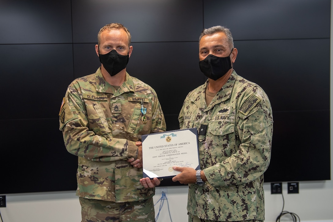 Rear Admiral Darius Banaji, DPAA Deputy Director for Operations, presents DPAA teammate, Sgt. 1st Class Jeremy Gleason, the Joint Service Commendation Medal  for rendering life-saving aid.  On June 5, Gleason, from the Surgeon General Directorate, provided emergency medical care to a member of the local community.  While waiting to participate in an event at Ke’ehi Lagoon in Honolulu, he immediately brought his training and skills to bear in responding to an individual experiencing cardiorespiratory arrest.  He administered both CPR and defibrillation to the individual, ultimately saving the person’s life.