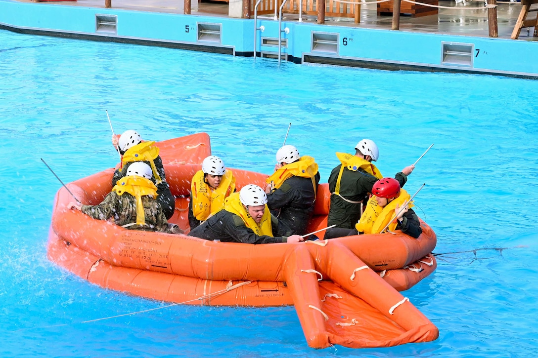 A group of airmen float on an orange inflatable in a swimming pool.