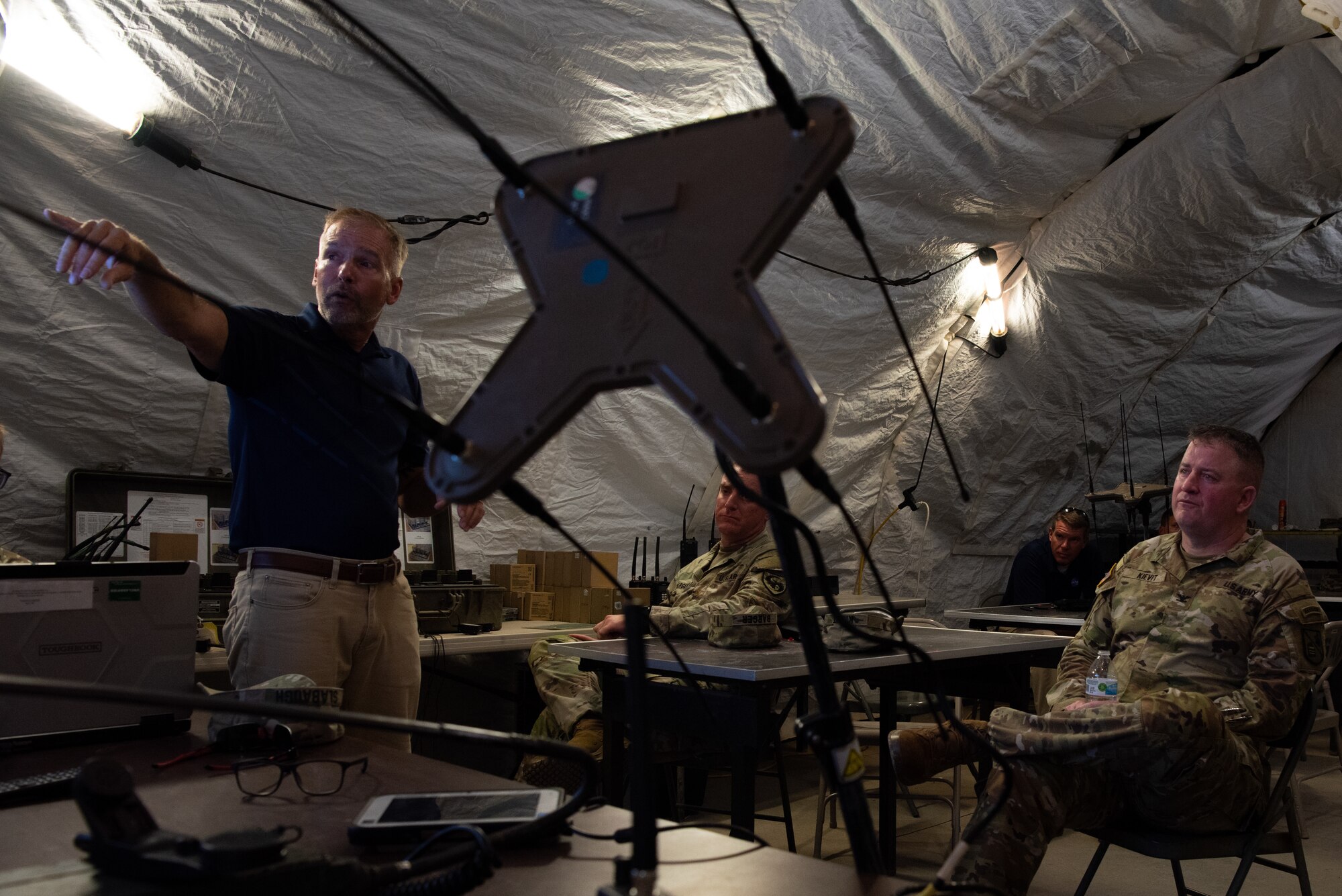 Tactical Signals Intelligence Exercise supervisor Brian LeMaster, 344th Military Intelligence Battalion, briefs U.S. Army Col. James A. Kievit, Defense Language Institute Foreign Language Center commandant, during a tour of Forward Operating Base Sentinel, Goodfellow AFB, Texas, July 12, 2022. FOB Sentinel is used during the 344th MI BN capstone exercise, where soldiers use their training in a simulated combat environment. (U.S. Air Force photo by Senior Airman Michael Bowman)