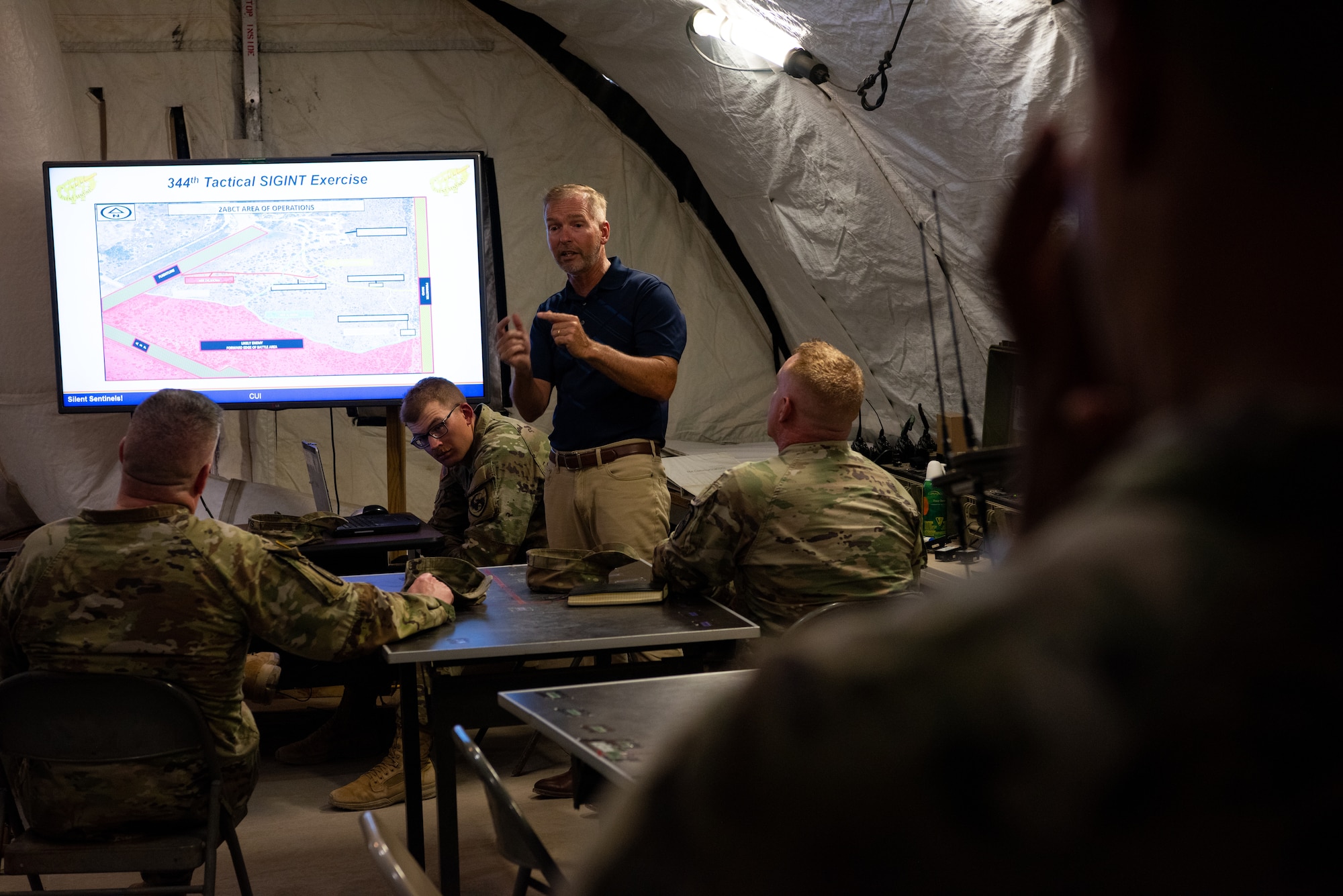 Tactical signals intelligence exercise supervisor Brian LeMaster, 344th Military Intelligence Battalion, briefs U.S. Army Col. James A. Kievit, Defense Language Institute Foreign Language Center commandant, during a tour of Forward Operating Base Sentinel, Goodfellow Air Force Base, Texas, July 12, 2022. FOB Sentinel is used during the 344th MI BN capstone exercise, where Soldiers use their training in a simulated combat environment. (U.S. Air Force photo by Senior Airman Michael Bowman)