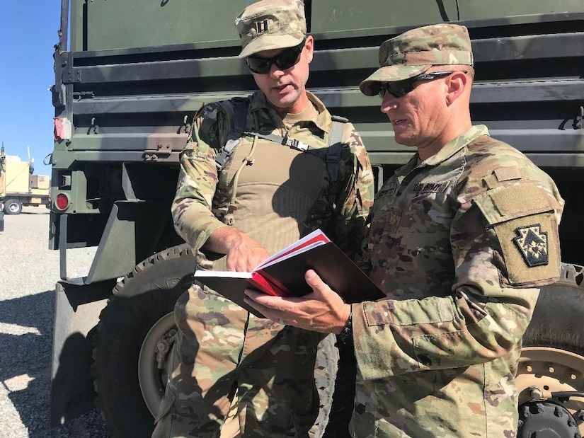Maj. Len Cowitch (right), legal adviser with the 213th Regional Support Group and a member of the senior trainer team which supported the 56th Stryker Brigade Combat Team’s National Training Center Rotation, meets with Capt. Edward Yost, the 56th Stryker Brigade Combat Team judge advocate, at a National Training Center assembly area June 24. STT members met periodically with their 56SBCT counterparts throughout the NTC rotation.