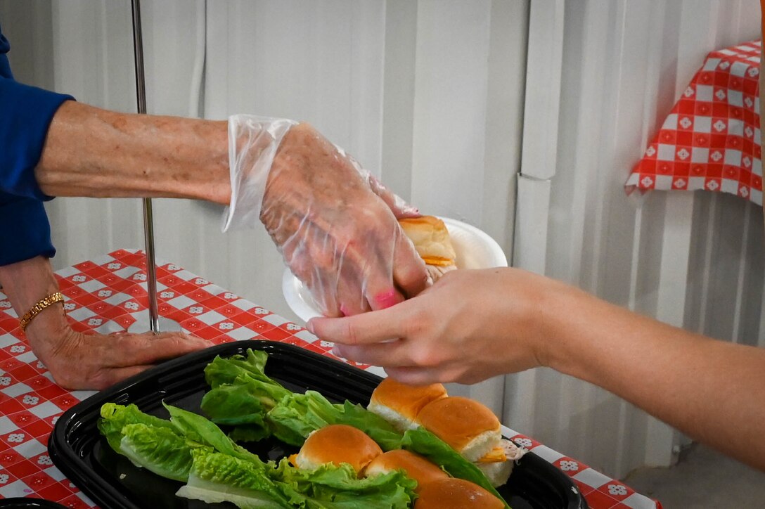 A Committee of 100 member hands a sandwich to Staff Sgt. Breanna Klemm, 97th Air Mobility Wing Public Affairs journeyman, at the “Taste of Altus” event, July 11, 2022. While all are welcome, Altus’ Committee of 100 hosts the event specifically to greet new community members, Airmen and their families. (U.S. Air Force photo by Senior Airman Kayla Christenson)