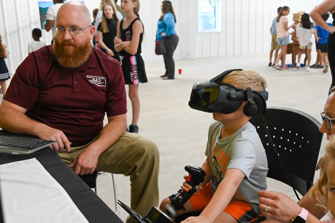 A child uses a flight simulator at the “Taste of Altus” event, July 11, 2022. Along with food vendors, there were also games and simulators for attendees to use. (U.S. Air Force photo by Senior Airman Kayla Christenson)