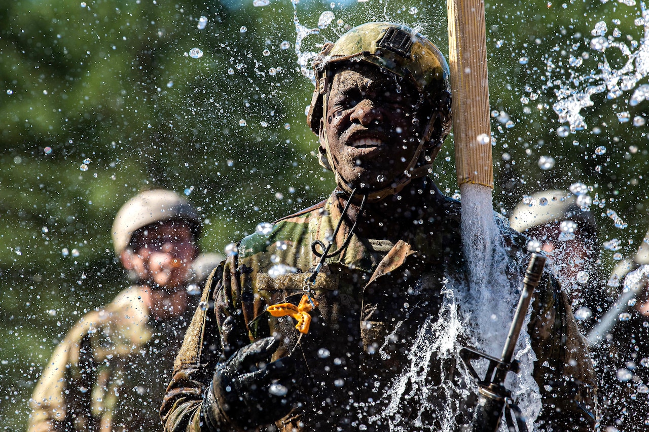 Water pours down on a grimacing cadet.