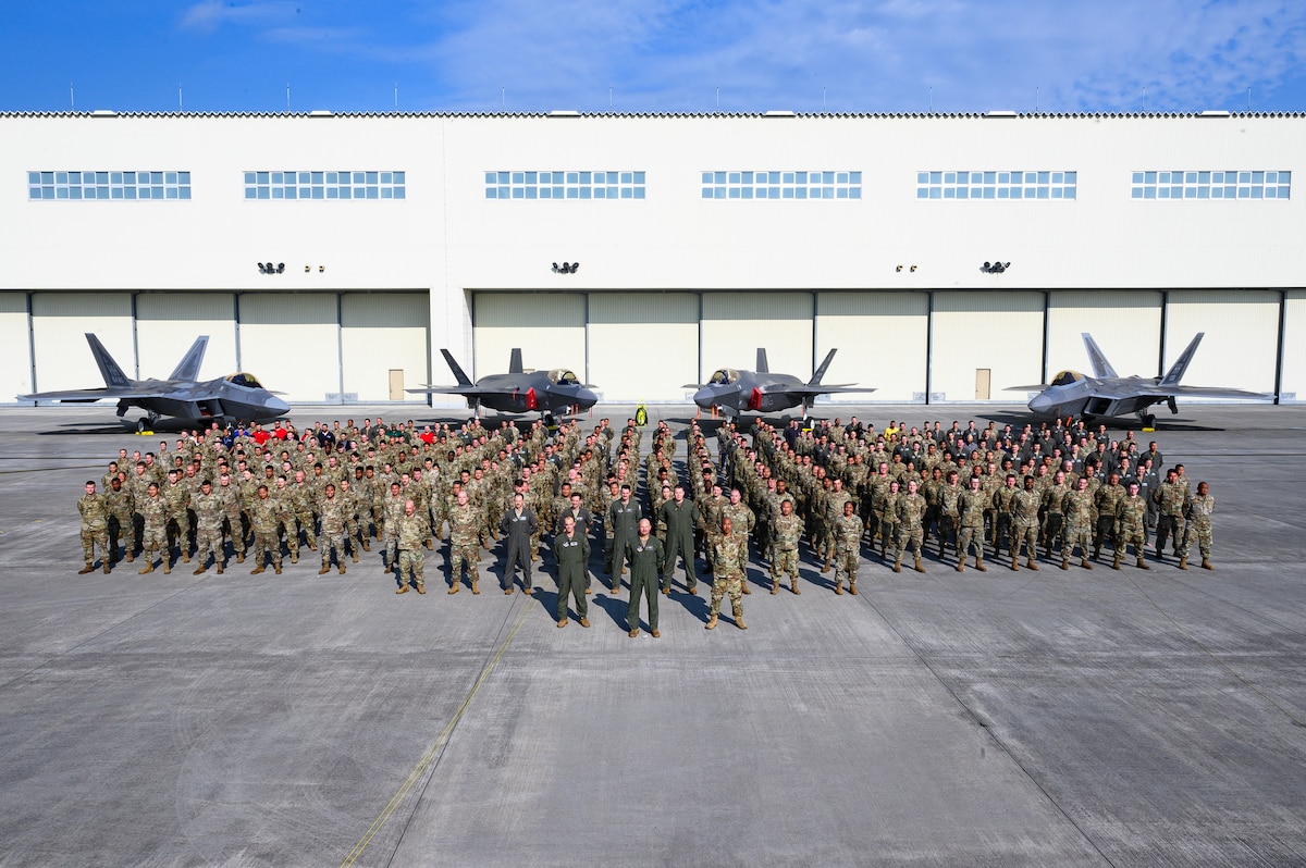 U.S. Airmen and personnel assigned to the 354th Air Expeditionary Wing pose for a group photo in front of two F-35A Lightning IIs and two F-22 Raptors at Marine Corps Air Station Iwakuni, Japan, June 23, 2022.