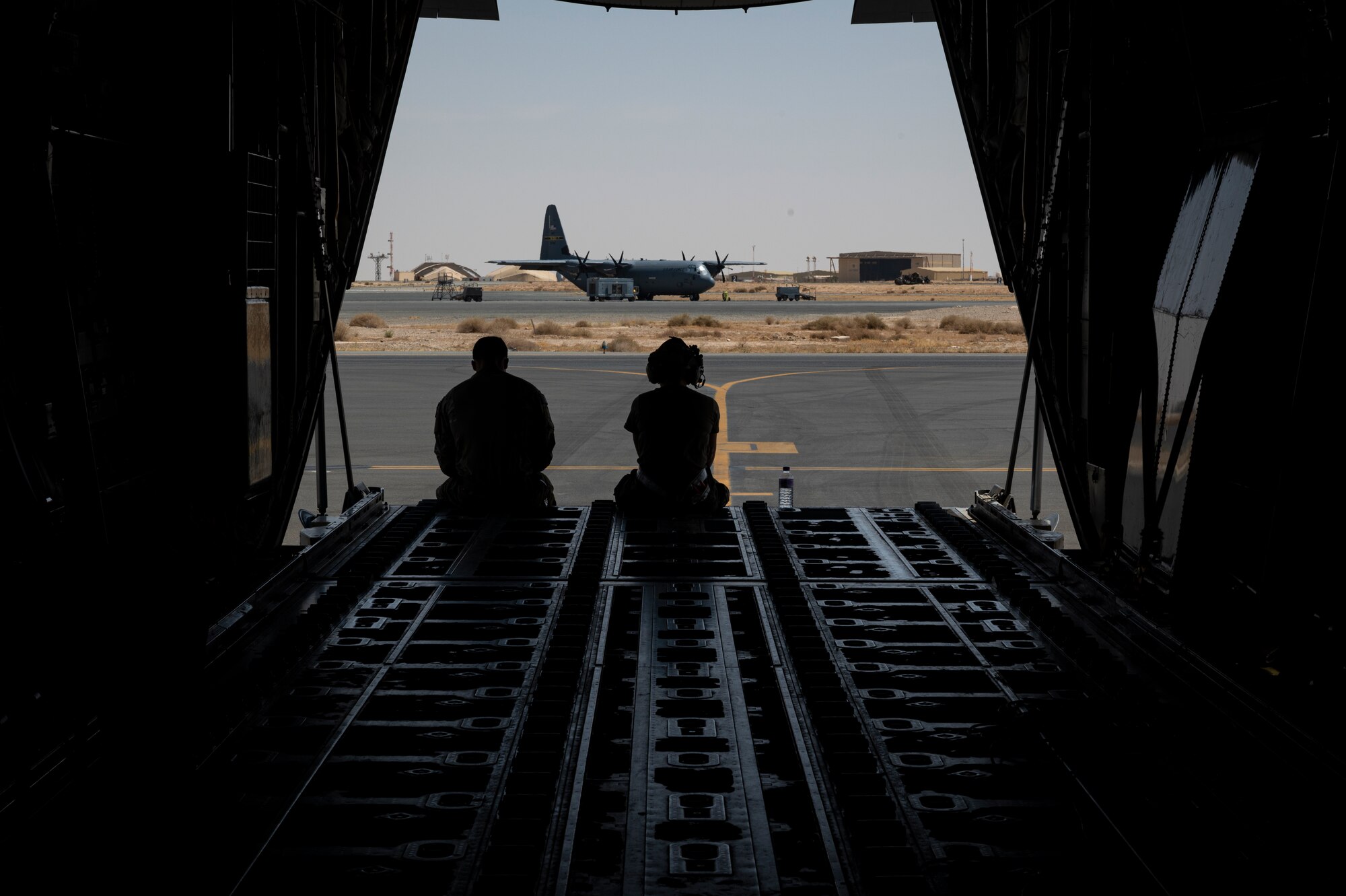 U.S. Air Force Tech. Sgt. Anthony Miller, left, and Senior Airman Carolyn Hendrix, right, 41st Expeditionary Squadron loadmasters, wait for for their mission to start on a C-130J Super Hercules