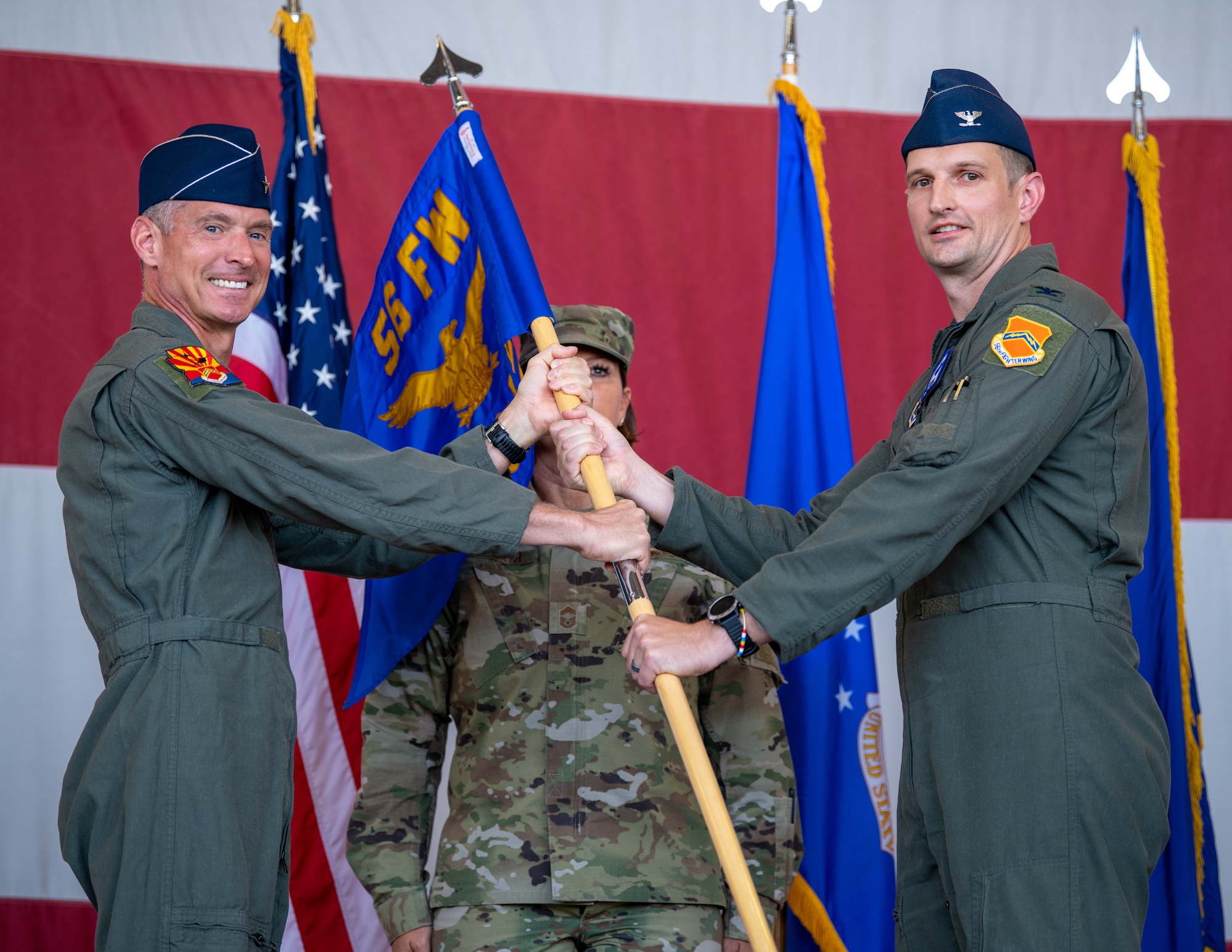U.S. Air Force Brig. Gen. Gregory Kreuder, 56th Fighter Wing commander (left), hands a guidon to Col. Matthew Johnston, 56th Operations Group commander (right), during the 56th OG change of command ceremony June. 3, 2022, at Luke Air Force Base, Arizona.