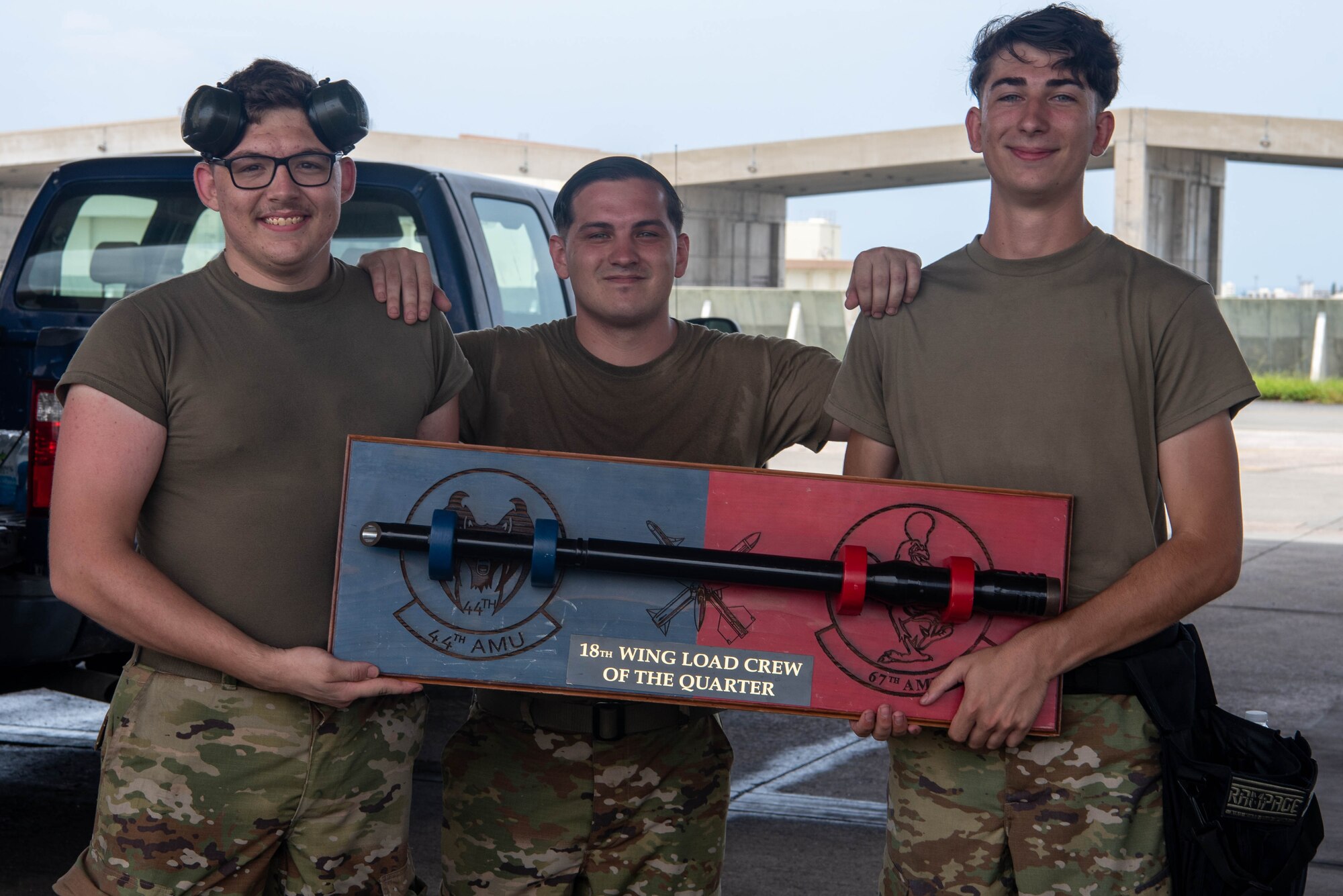 Three Airmen pose with a trophy after winning the F-15 Load Crew of the Quarter Competition at Kadena Air Base, Japan, July 15, 2022.