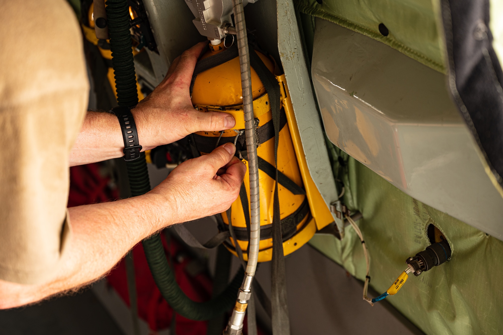 U.S. Air Force Col. Randy D. Schwinler, Commander 379th Expeditionary Maintenance Group, Al Udeid Air Base, Qatar, reattaches a canister, used for fire suppression, back to the wall of a KC-135 Stratotanker, July 9, 2022. Schwinler conducted a pre-flight check to ensure safety of the aircraft prior to it being used for a flight. (U.S. Air Force photo by Staff Sgt. Dana Tourtellotte)