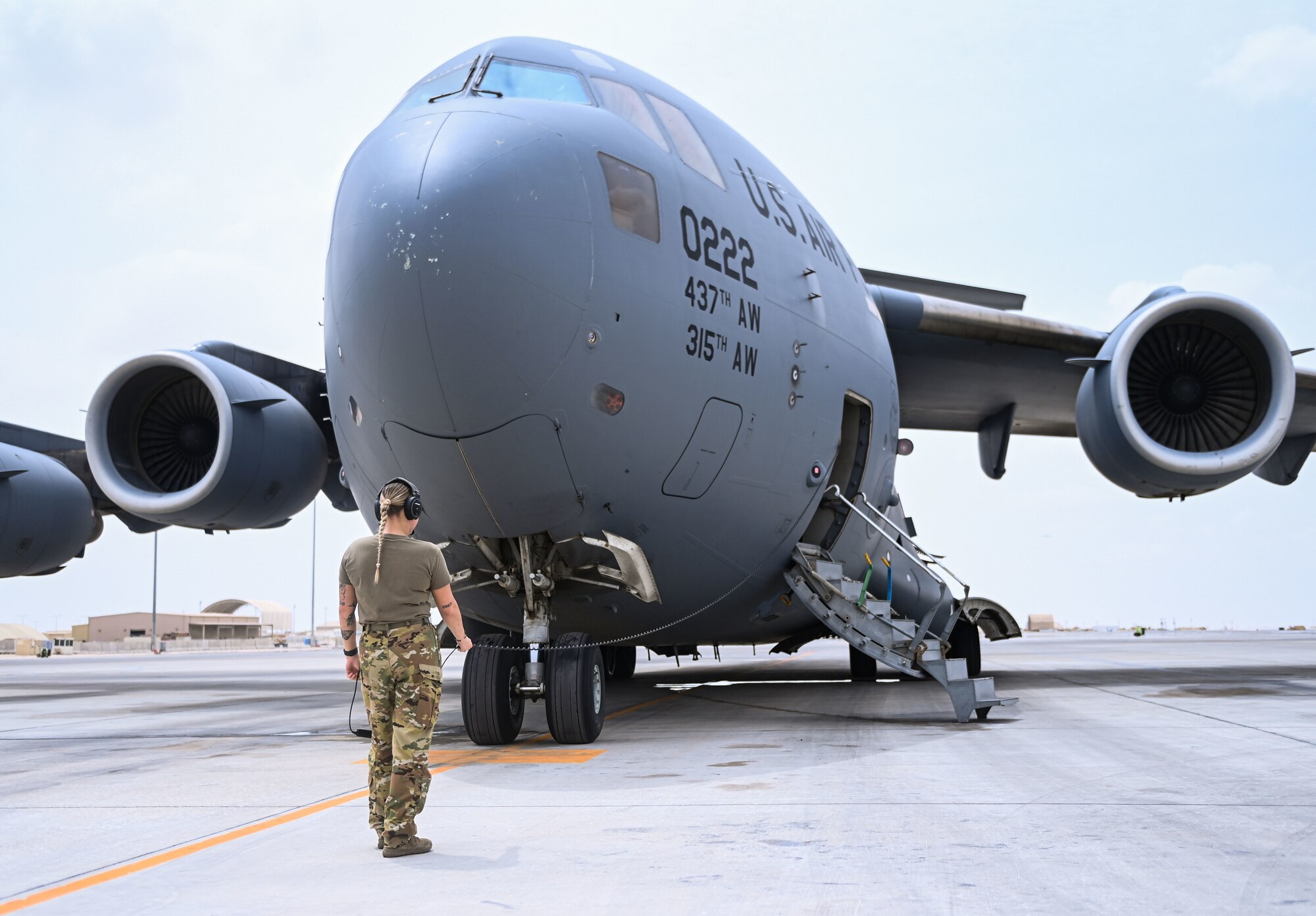 U.S. Air Force Airman 1st Class Mikaela Branchfield, an 816th Expeditionary Airlift Squadron loadmaster, communicates with pilots on board a C-17 Globemaster during a preflight check July 12, 2022 at Al Udeid Air Base, Qatar. C-17 aircraft can perform tactical airlift and airdrop missions and can transport litters and ambulatory patients during aeromedical evacuations. (U.S. Air National Guard photo by Tech. Sgt. Michael J. Kelly)