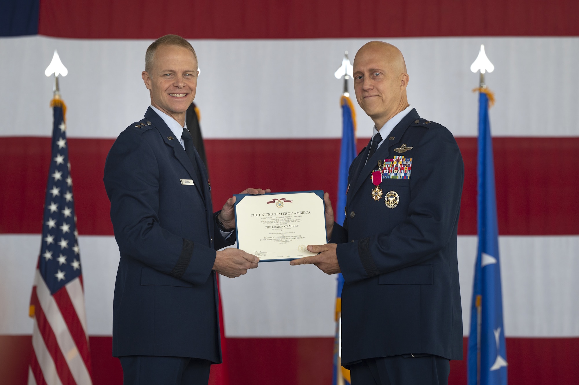 U.S. Air Force Brig. Gen. Josh Olson, outgoing 86th Airlift Wing commander, right, receives a legion of merit award from Maj. Gen. Derek France, Third Air Force commander, during a change of command ceremony at Ramstein Air Base, Germany, July 15, 2022. Olson received the award for meritorious service during his time as the 86 AW commander. (U.S. Air Force photo by Senior Airman Andrew Bertain)