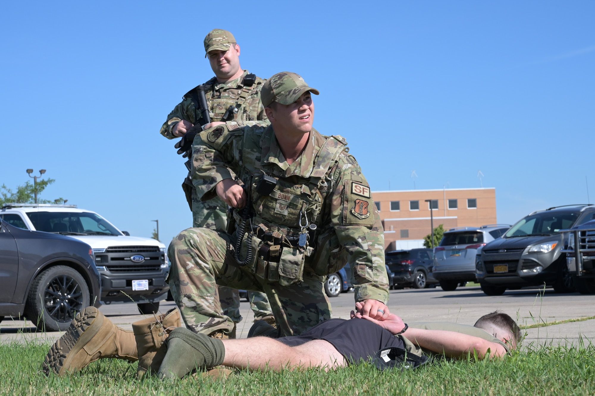 an Airman searches a simulated intruder held on the ground