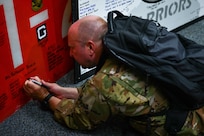 Royal Air Force Capt. Christopher Knight, 14th Airlift Squadron pilot, signs a runway panel from Afghanistan