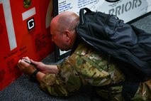 Royal Air Force Capt. Christopher Knight, 14th Airlift Squadron pilot, signs a runway panel from Afghanistan