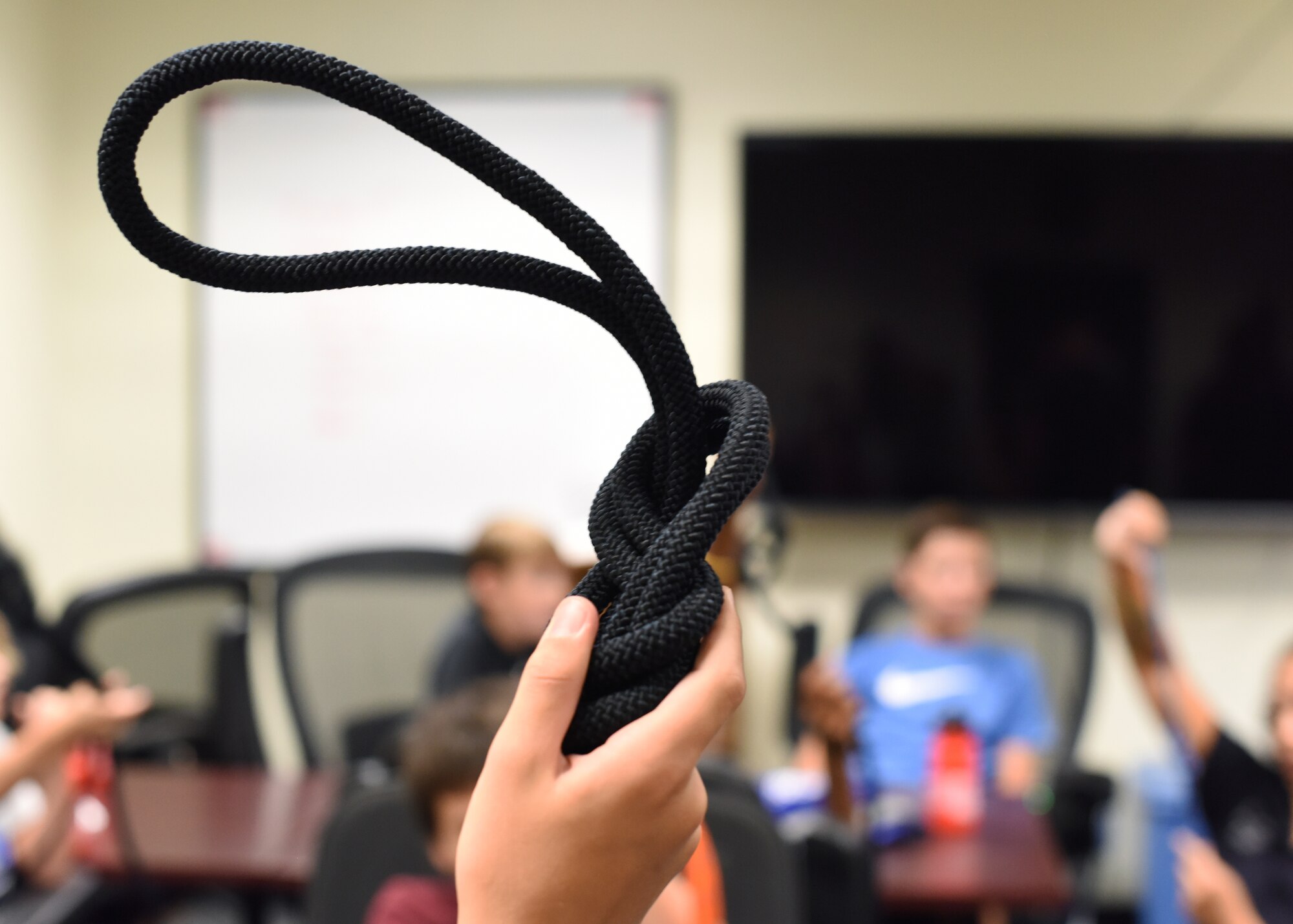 A junior firefighter student holds up a figure-eight knot during class, at Goodfellow Air Force Base, Texas, July 13, 2022. Students of the junior firefighter camp were taught multiple variations and uses of the figure 8 knots. (U.S. Air Force photo by Airman 1st Class Zachary Heimbuch)