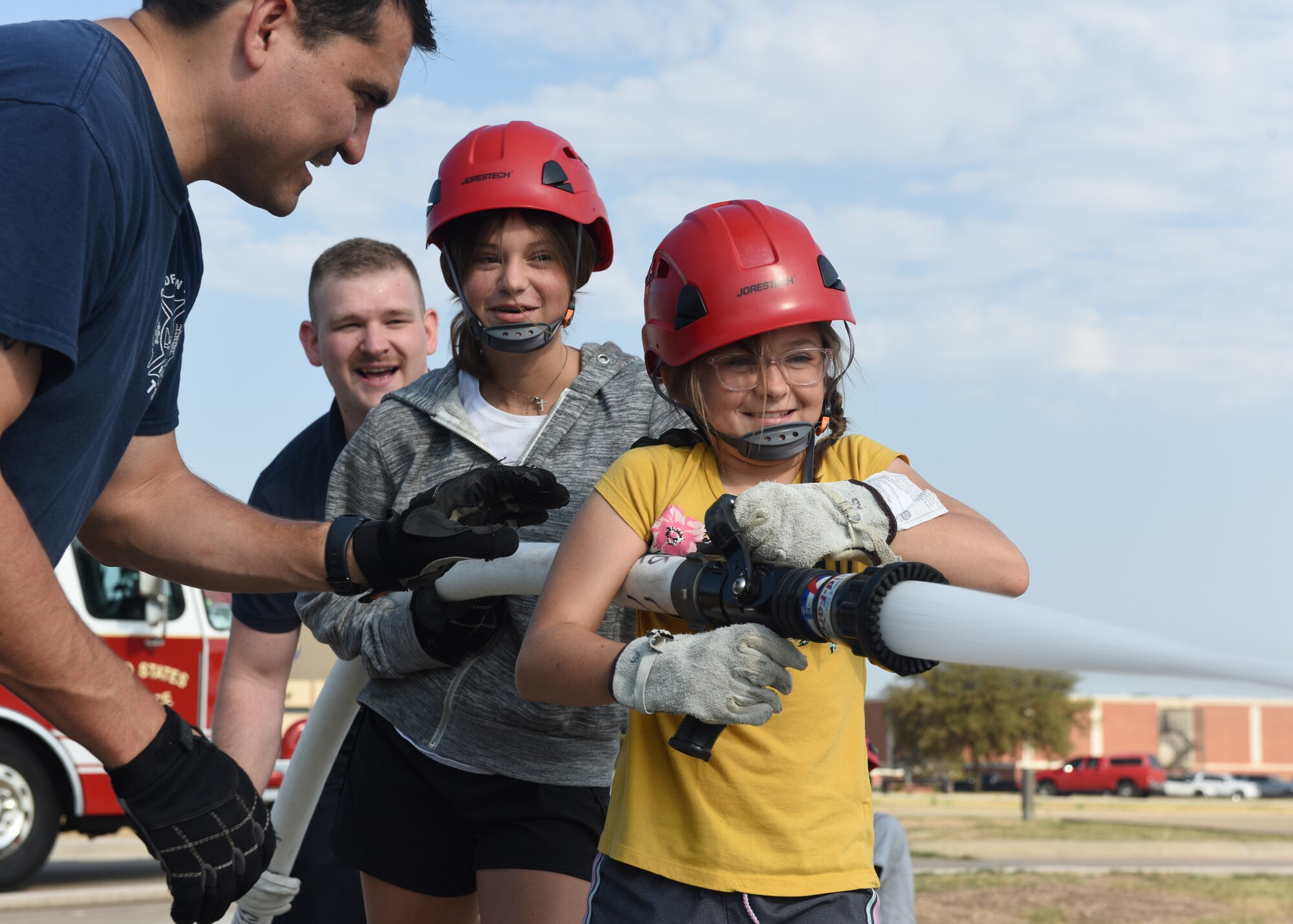 Paige and Karsyn Ramsdell, junior firefighter camp students, operate a fire hose during the fire hose evolutions class, at Goodfellow Air Force Base, Texas, July 14, 2022. The students sprayed a simulated fire by using the hose to knock over cones. (U.S. Air Force photo by Airman 1st Class Zachary Heimbuch)